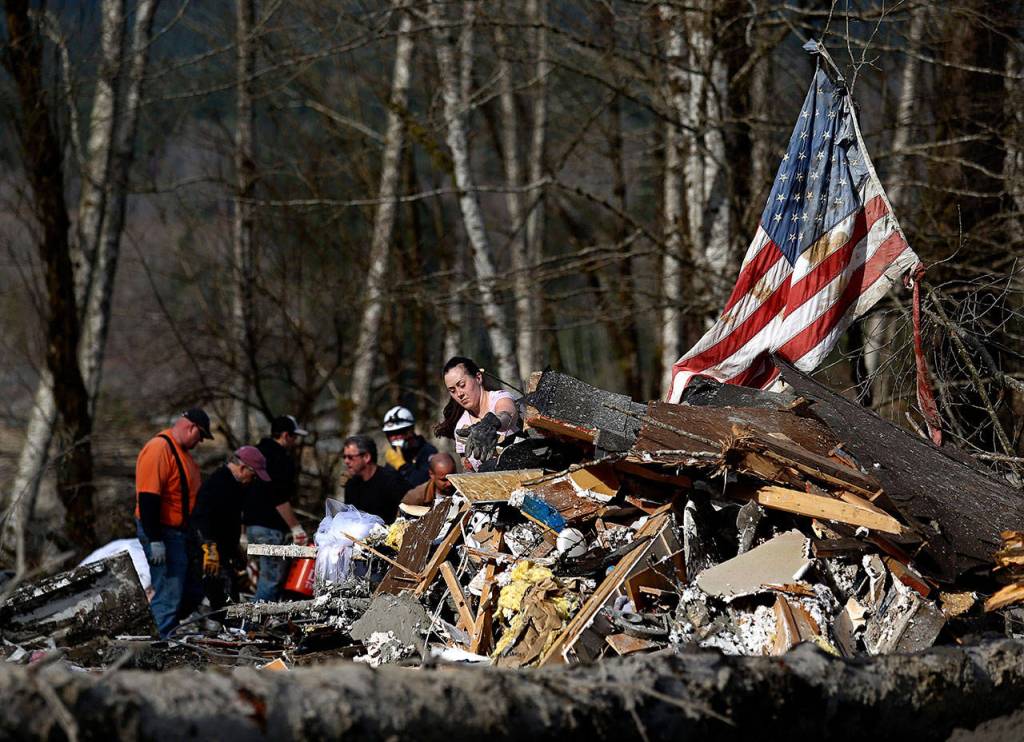 Natasha Huestis (center) clears debris on March 24, 2014, while searching at the site of a destroyed house pushed onto Highway 530 in Oso. (Dan Bates / The Herald)