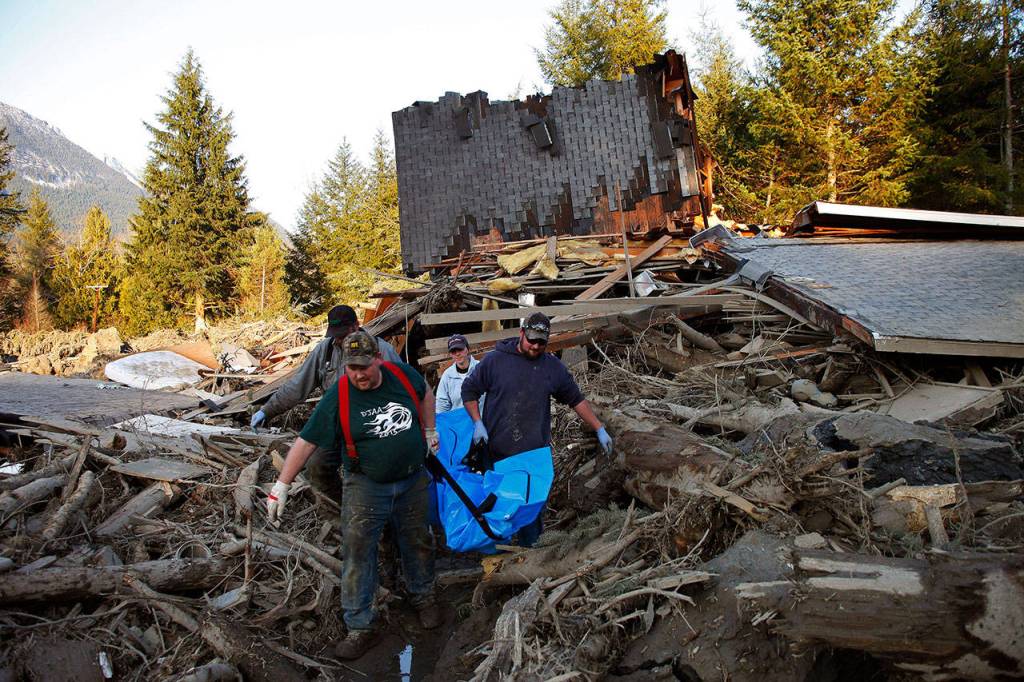 Jason Anderson, Steve Skaglund, Rhonda Cook and Frank Cook recover a body from the wreckage on March 23, 2014. (Genna Martin / The Herald)