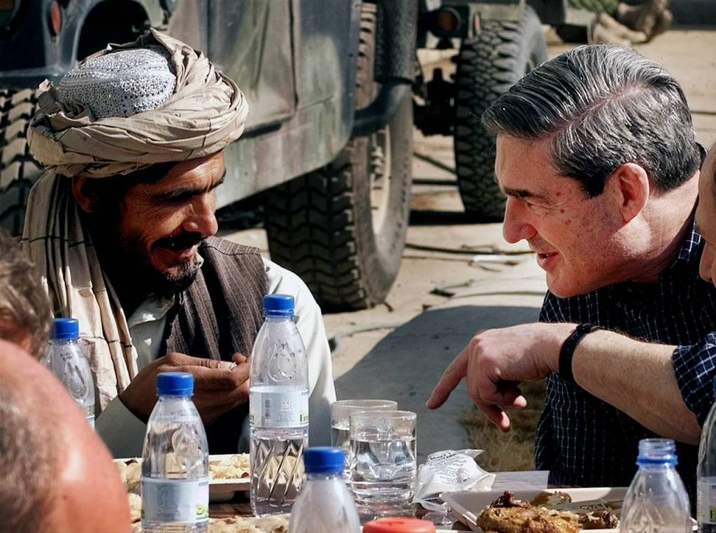FBI Director Robert Mueller (right) talks with Kandahar intelligence chief Haji Gulali during an informal lunch in the courtyard inside the airport terminal at the air base on Jan. 23, 2002, in Kandahar, Afghanistan. (AP Photo/Pablo Martinez Monsivais, file)