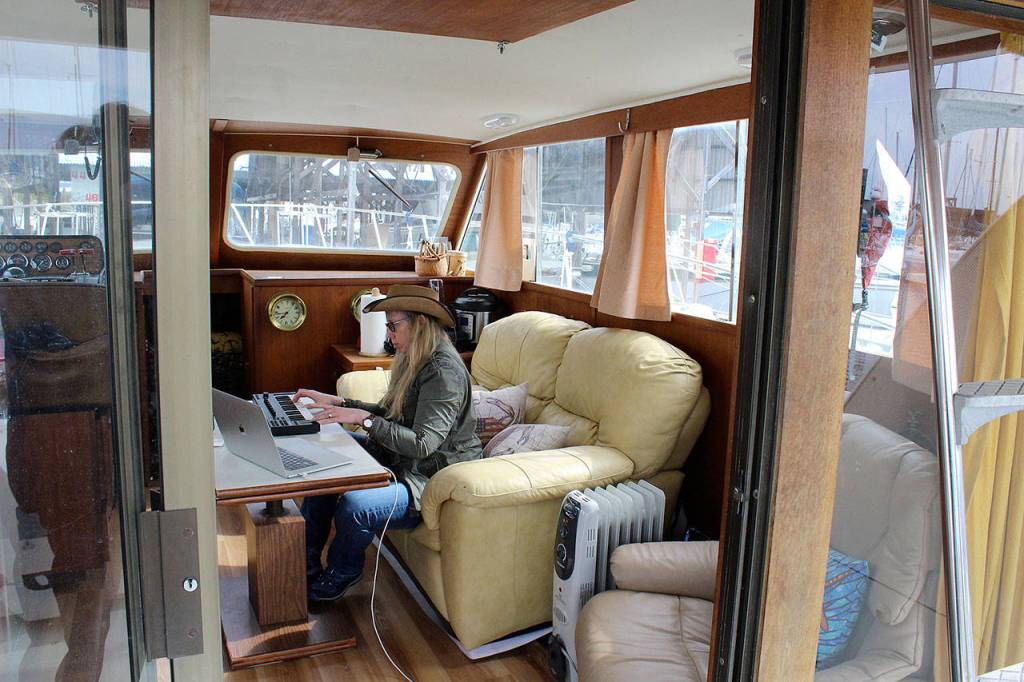 Holly Chadwick works aboard her boat, Rubicon, where she lives at Oak Harbor Marina. (Patricia Guthrie / Whidbey News Group)