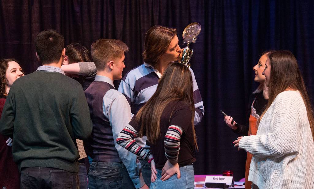 As his teammates celebrate their win, Jake Spores kisses a trophy after Stanwood High won the Hi-Q academic quiz competition championship held at Stanwood High School March 22. Stanwood beat out Monroe and Archbishop Murphy for the win. (Andy Bronson / The Herald)