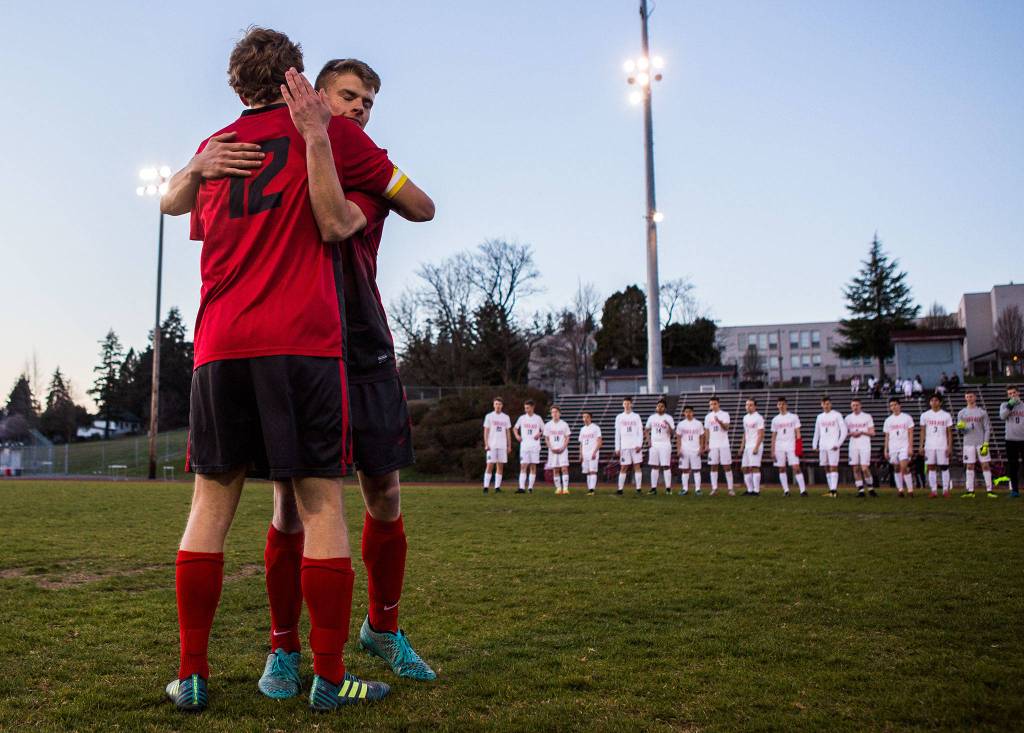 Stanwood seniors Corey Mourges (left) and Ben Dahlberg (right) hug before the game against Mountlake Terrace on March 26 in Stanwood. It was the seniors last game on their home field before construction begins. (Olivia Vanni / The Herald)