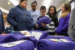 Sixth-graders at College Place Elementary School read notes that were written to accompany blankets the students were planning to give out to people experiencing homelessness. (Lizz Giordano / The Herald)