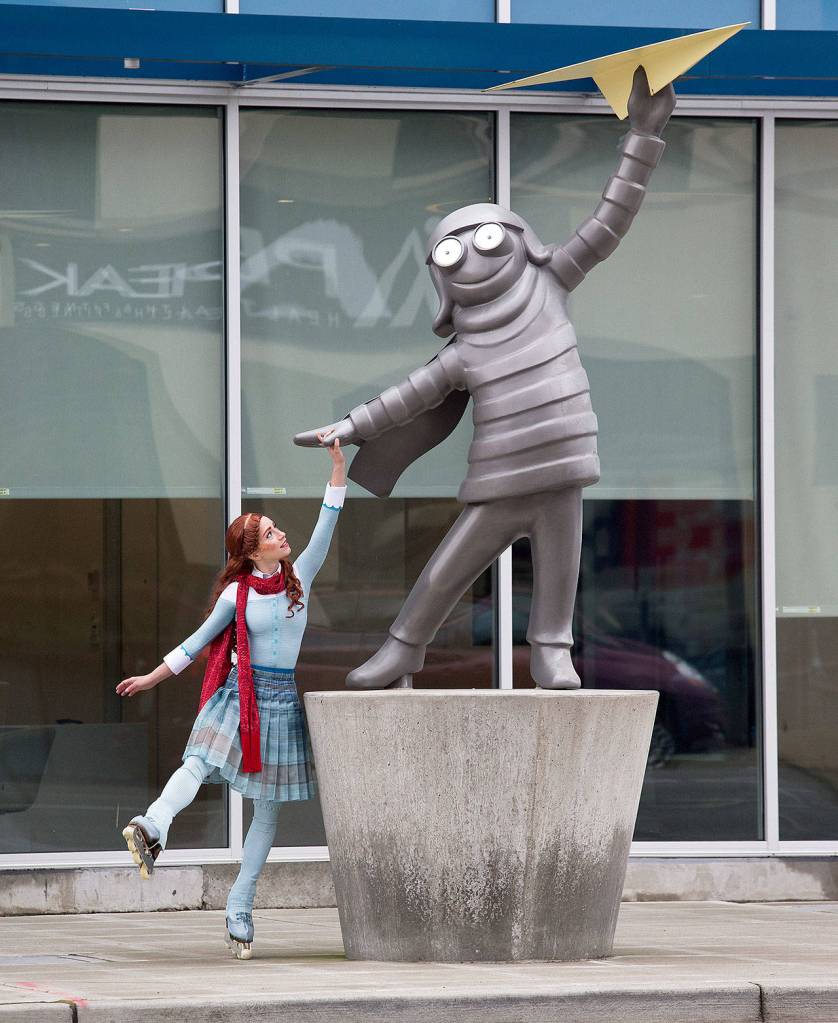 Silja Dos Reis holds the hand of the statue Someday in front of the the Aero Apartments in Everett. (Andy Bronson / The Herald)