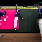 Edmonds-Woodway players jump to see how high they can reach above the back wall at T-Mobile Park prior to the game. (Olivia Vanni / The Herald)