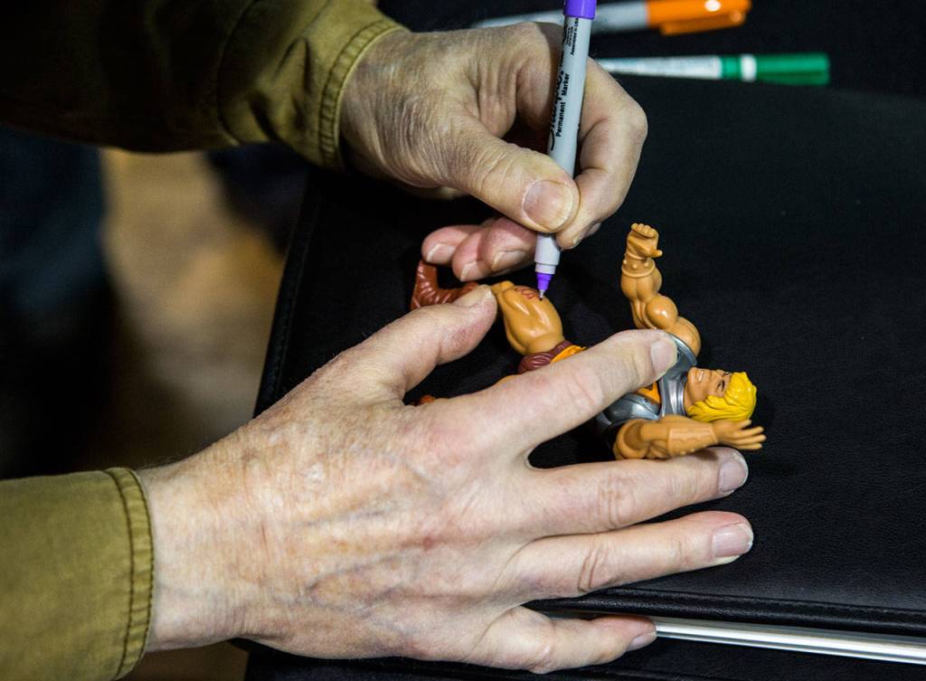 Roger Sweet signs a He-Man battle action figurine Saturday, April 13 at BobaKhan Toys & Collectibles in Everett. (Olivia Vanni / The Herald)