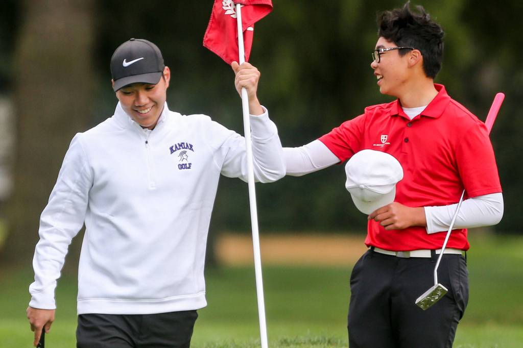 Kamiaks Alvin Kwak (left) shares a laugh with Riley Lai of St. Georges (British Columbia) while replacing the flag on the 18th hole. Kwak and Lai were the tournaments top two finishers. (Kevin Clark / The Herald)