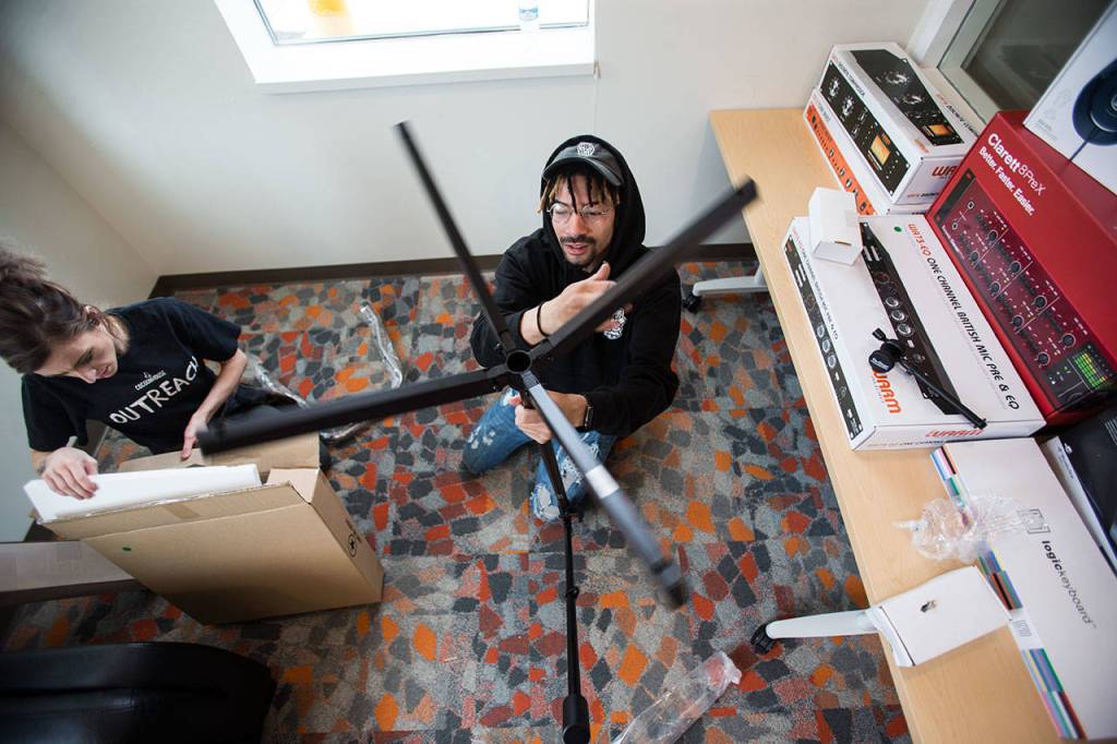 Raph Echols, Cocoon Houses music program coordinator, builds a microphone stand as Jill Costello unpacks equipment in the recording studio in the new Cocoon House on Colby Avenue Tuesday. (Andy Bronson / The Herald)