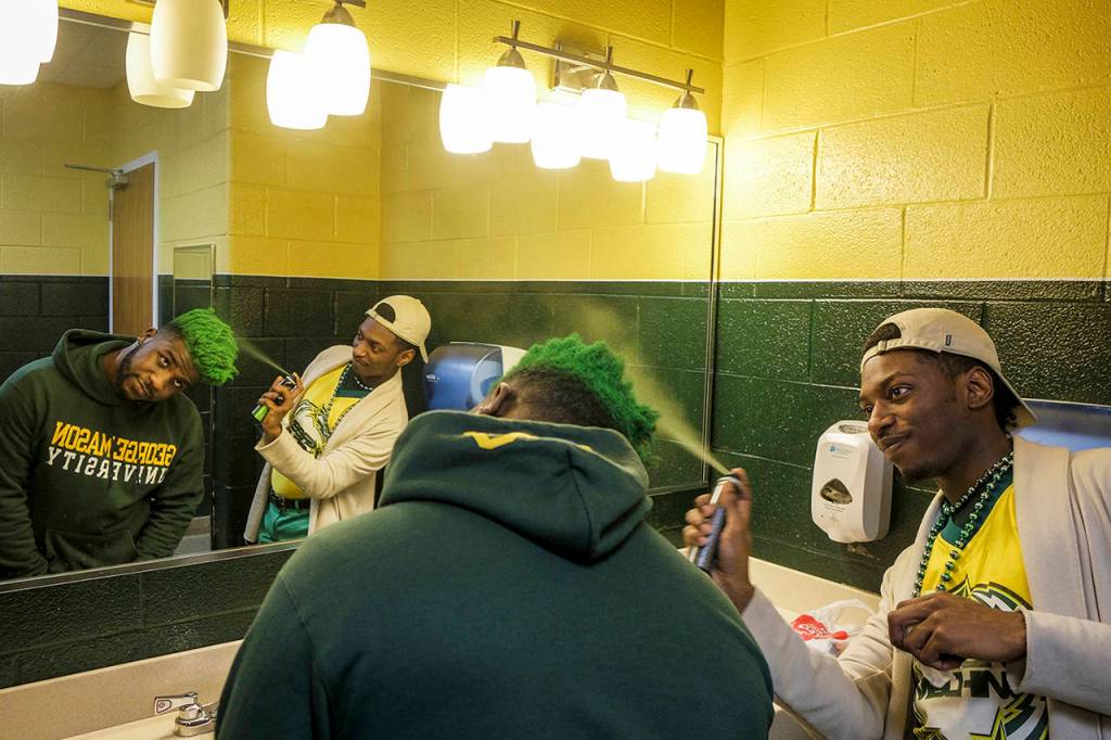 Friend and fellow bandmate Wagnus Prioleau sprays Adamss hair green before a school pep rally at an event known as Mason Madness that kicks off GMUs basketball season. (Jahi Chikwendiu/Washington Post)