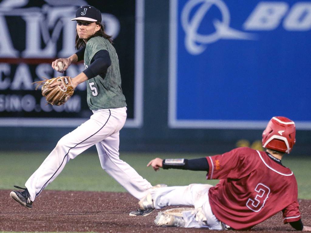 Jacksons Dylan Anders throws to first after tagging out Cascades Benjamin Hansen at Everett Memorial Stadium on April 5. (Kevin Clark / The Herald)