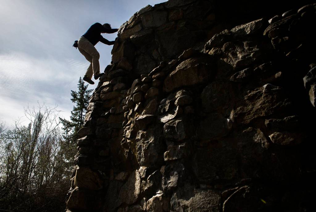 Jeff Smoot begins climbing down Schurman Rock at Camp Long on April 2 in Seattle. (Olivia Vanni / The Herald)