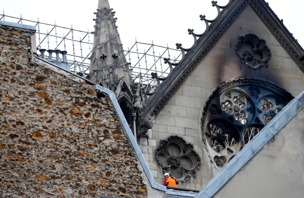 A man is pictured near chared glass windows Notre Dame cathedral on Tuesday in Paris. Firefighters declared success Tuesday in a more than 12-hour battle to extinguish an inferno engulfing Paris iconic Notre Dame cathedral that claimed its spire and roof, but spared its bell towers. (AP Photo/Francois Mori)