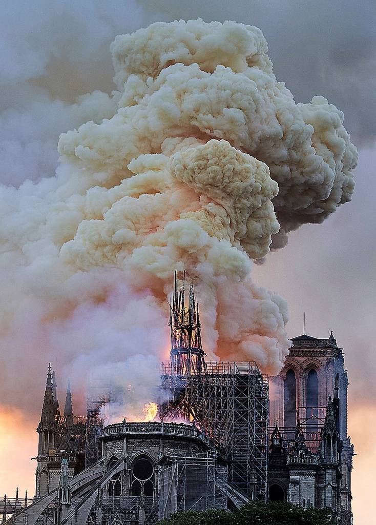 Flames and smoke rise as the spire on Notre Dame cathedral collapses in Paris on Monday. Massive plumes of yellow brown smoke filled the air above Notre Dame Cathedral. (AP Photo/Diana Ayanna)