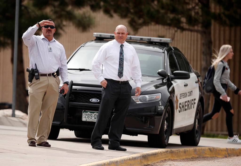 Columbine High School principal Scott Christy (right) joins an officer in watching as students leave the school late Tuesday in Littleton, Colorado. (AP Photo/David Zalubowski)