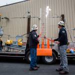 Lineman Travis Boortz, left, and Jake Morgan, right, demonstrate the electrical arc when a metal ladder comes close to a live electrical wire during a demonstrationWednesday in Everett. (Olivia Vanni / The Herald)