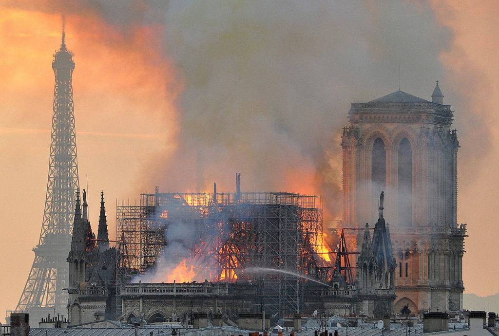In this image made available on Tuesday April 16, 2019 flames and smoke rise from the blaze after the spire toppled over on Notre Dame cathedral in Paris, Monday, April 15, 2019. An inferno that raged through Notre Dame Cathedral for more than 12 hours destroyed its spire and its roof but spared its twin medieval bell towers, and a frantic rescue effort saved the monuments most precious treasures, including the Crown of Thorns purportedly worn by Jesus, officials said Tuesday. (AP Photo/Thierry Mallet)