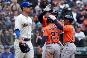 Seattle Mariners starting pitcher Marco Gonzales, left, heads back to the mound as Houston Astros Jose Altuve (27) and Tony Kemp (18) celebrate scoring with Carlos Correa in the sixth inning of a baseball game Sunday, April 14, 2019, in Seattle. (AP Photo/Elaine Thompson)