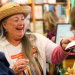 Elaine Mattson reaches to stamp an Independent Bookstore Day Challenge passport at Edmonds Bookshop. (Kevin Clark / The Herald)