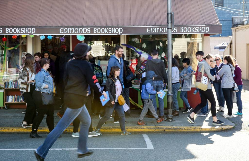 Customers, with passports in hand, line up for a stamp outside Edmonds Bookshop. (Kevin Clark / The Herald)