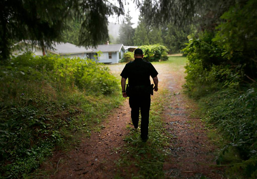 Arlington police Sgt. Rob Martin walks past where Robert Endrizzi lie (behind berm on left) near the drive to his home, firing a rifle at people and vehicles on Jim Creek Road, until he was killed by the SWAT team Martin led in September 2012. (Dan Bates / The Herald)
