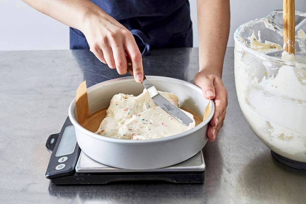 While greasing your cake pans, slide a round piece of parchment on the bottom. (Photo for The Washington Post by Stacy Zarin Goldberg; styling by Lisa Cherkasky)
