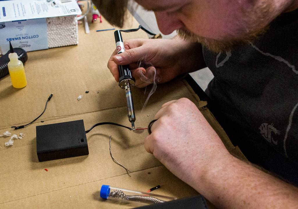 Levi Cline solders wires for his groups sh*tty robot at TheLab@everett. (Olivia Vanni / The Herald)