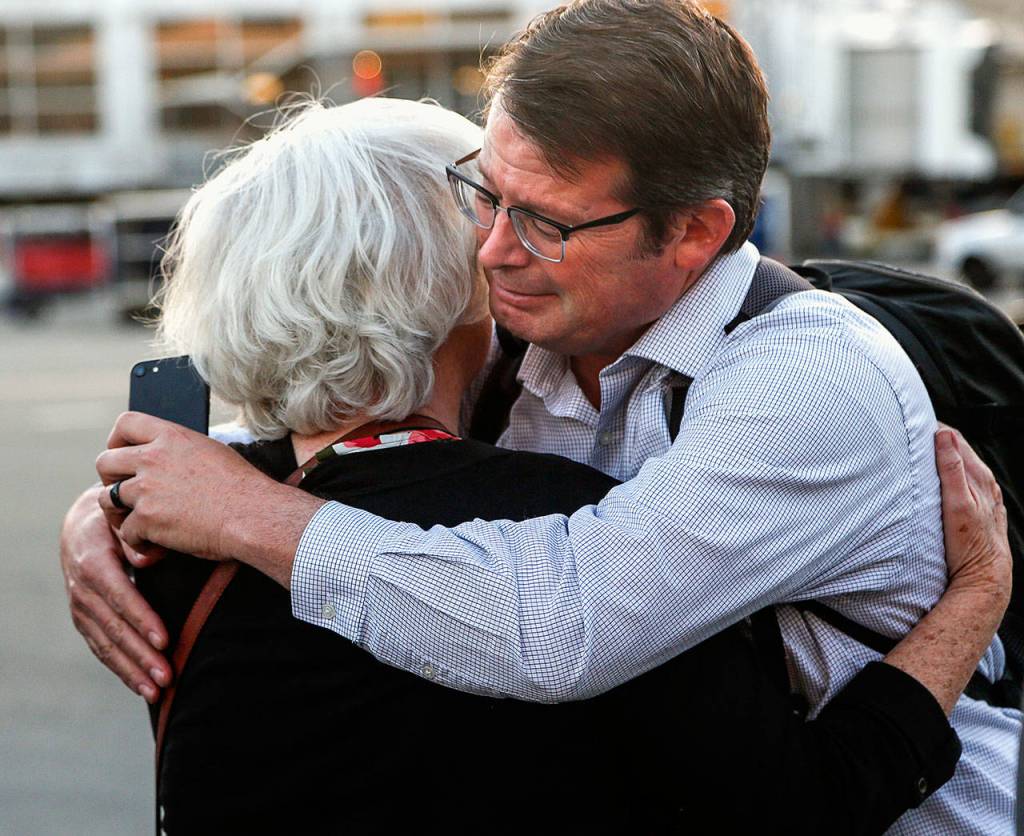 During the plane-side ceremony at Sea-Tac, John Price gets a hug from his mother, Judy Price, 74. Judys mother was the sister of Daniel Guisinger, an Everett sailor killed at Pearl Harbor. (Dan Bates / The Herald)