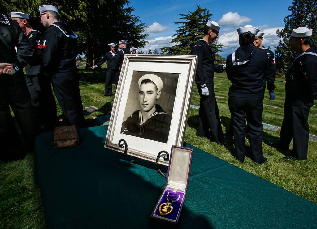 A portrait of Seaman 1st. Class Daniel Guisinger Jr. and his Purple Heart medal are displayed as sailors wait to take part in his burial service at Cypress Lawn Memorial Park in his hometown of Everett. (Dan Bates / The Herald)