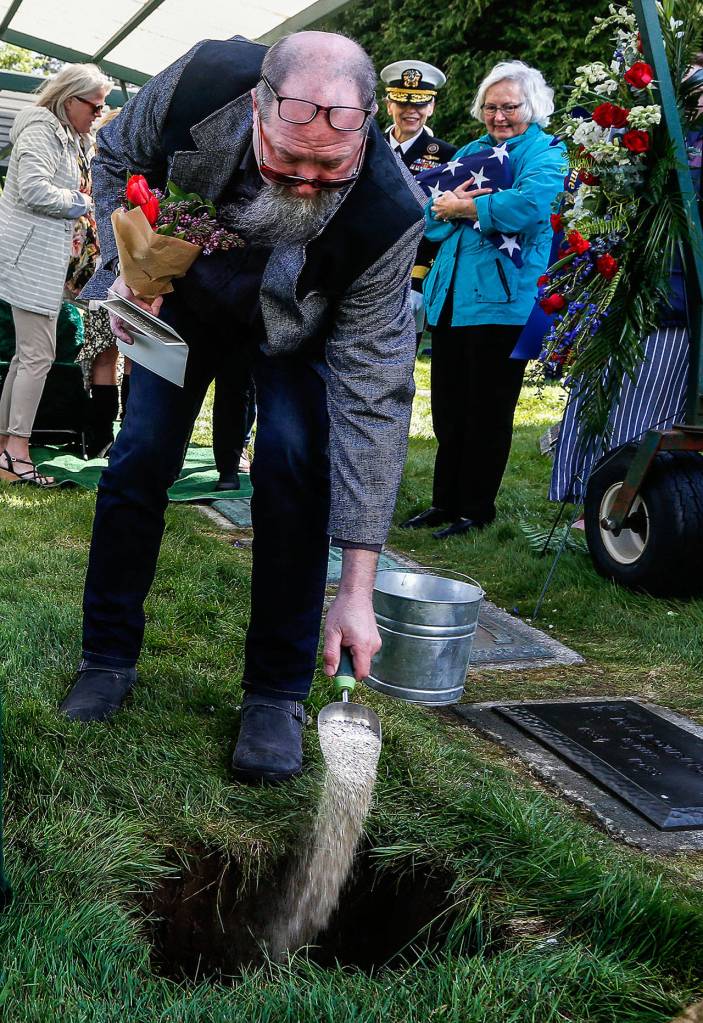 Craig Williams, whose great uncle was Daniel Guisinger Jr., pours sand into the grave that holds an urn bearing the ashes of the Everett sailor who died at Pearl Harbor. Guisinger was buried with military honors on April 27. (Dan Bates / The Herald)