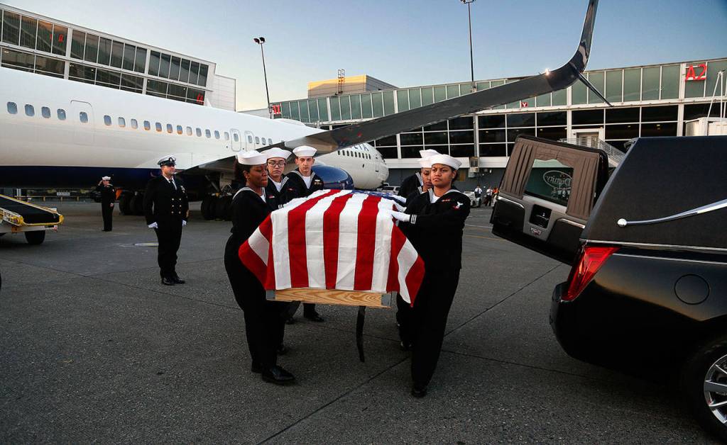 A Navy honor guard carries the flag-draped casket holding the remains of Everett sailor Daniel Guisinger, who was killed at Pearl Harbor. Passengers aboard the Delta Air Lines flight that carried the casket remained on the plane during the ceremony. (Dan Bates / The Herald )