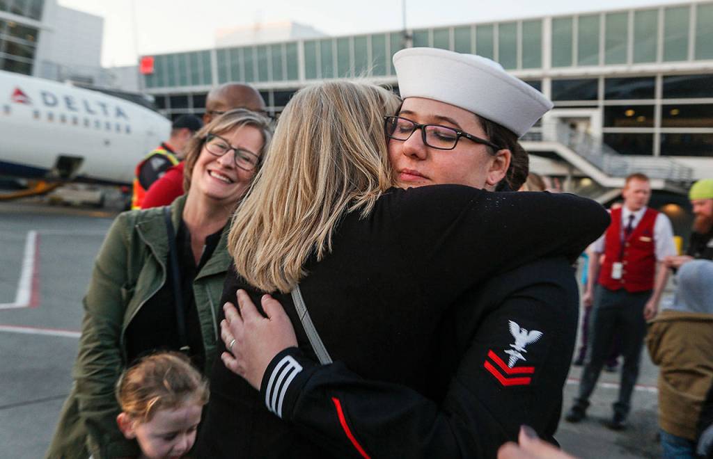 A Navy escort, Hospital Corpsman 2nd Class Stephanie Kitchen, traveled on every flight of the journey that brought Daniel Guisingers remains home to Washington. Here, she hugs a family member as RuthAnn Hoeglund looks on at Sea-Tac Airport. (Dan Bates / The Herald)