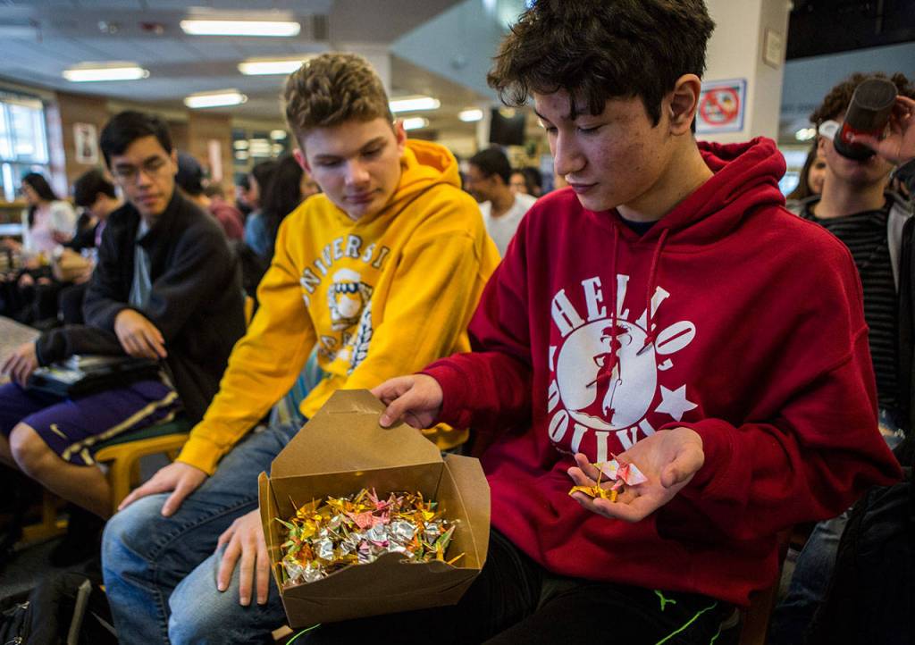 Sion Andrews takes two paper cranes out of a box that was provided at the end of Judy Kusakabes talk at Kamiak High School to promote a message of kindness. (Olivia Vanni / The Herald)