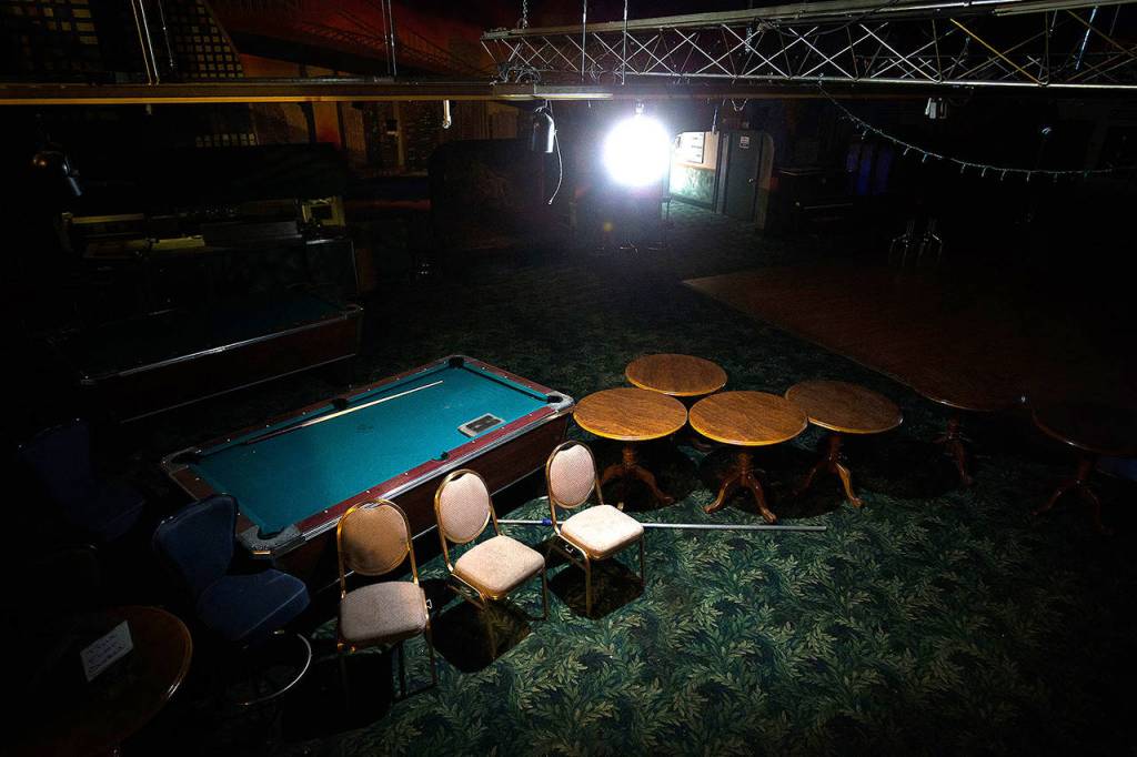A single light shines on abandoned pool tables, chairs and tables on the first floor inside of Club Broadway on May 1 in Everett. (Andy Bronson / The Herald)