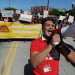 A protester yells into a bullhorn as he takes part in a march Wednesday for immigrant and workers rights on May Day in downtown Seattle. (AP Photo/Ted S. Warren)