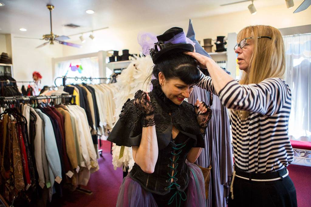 Owner Cyd Hand helps customer Barbara Kiesling try on a hat at Vintage Costumers in Everett. (Olivia Vanni / The Herald)