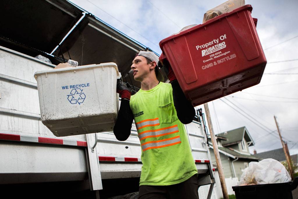 Jeremy Youngren, 20, an employee of Rubatino Refuse Removal, carries two recycling bins to his truck during his route on April 24 in Everett. (Olivia Vanni / The Herald)
