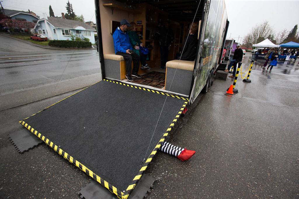 Legs, like those from a scene in the Wizard of Oz, stick out from under the ramp of The Big Shaker as it bounces like a magnitude seven-plus earthquake on April 19 in Everett. The Big Shaker is an earthquake simulator in a 24-foot trailer that replicates a typical living room of sofas and shelves with books and plastic dishes that fall during the demonstration. (Andy Bronson / The Herald)
