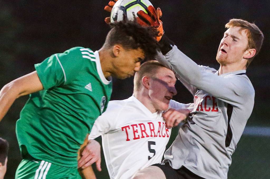 Edmonds-Woodways Zoumana Kone makes a header with Mountlake Terraces Ty Harris (center) defending and Ben Leonard making a grab at Edmonds-Woodway High School on April 30. (Kevin Clark / The Herald)