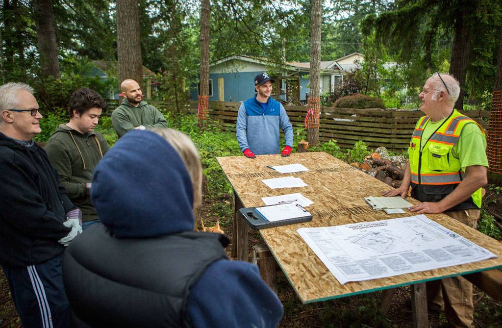 Construction manager Chris Anderson (right) talks to a group of volunteers during a Habitat for Humanity build on Saturday in Gold Bar. (Olivia Vanni / The Herald)