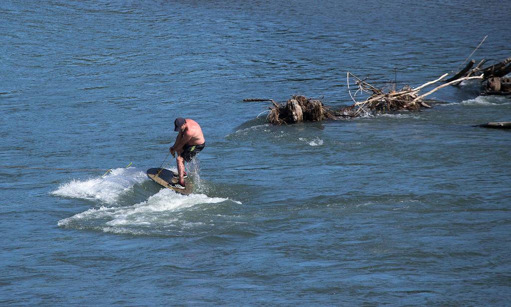 With his line attached to a nearby tree, a man wakeboards on the South Fork of the Stillaguamish River as temperatures hit the 80s on May 9 in Everett. (Andy Bronson / The Herald)