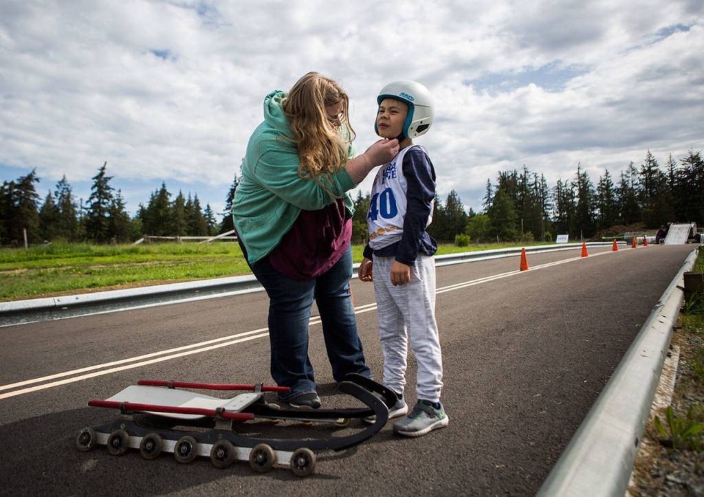Caden Delaney gets help adjusting his helmet during the USA Luge Slider Search program Sunday at Arrowhead Ranch on Camano Island. (Olivia Vanni / The Herald)