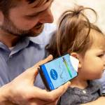 In this undated photo, Dr. Randall Bly uses a uses a phone app and a paper funnel to focus the sound, to check his daughter for an ear infection, at the UW School of Medicine in Seattle. (Dennis Wise/University of Washington via AP)