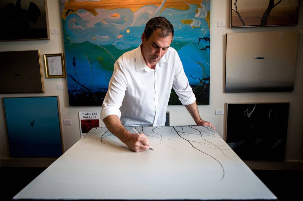 Michael Knutson demonstrates how he paints such fine lines in his art studio on May 13, 2019 in Everett. (Olivia Vanni / The Herald)