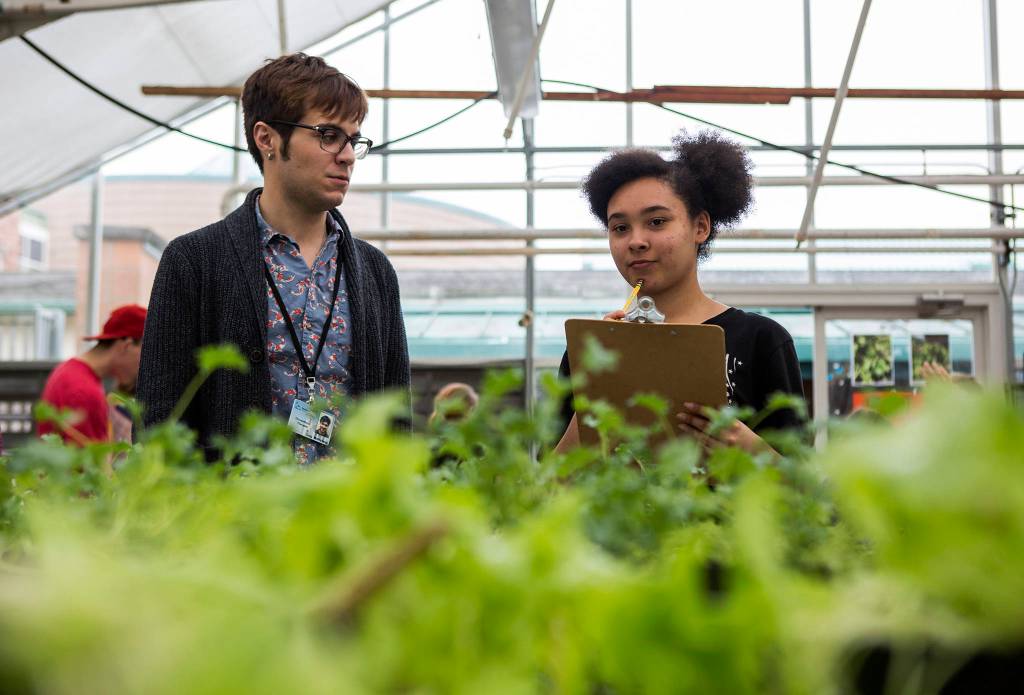 Greg McMichael (left) helps Emily Harris (right) with a plant order during the Functional Life Academics plant sale at Kamiak High School on May 14 in Mukilteo. (Olivia Vanni / The Herald)