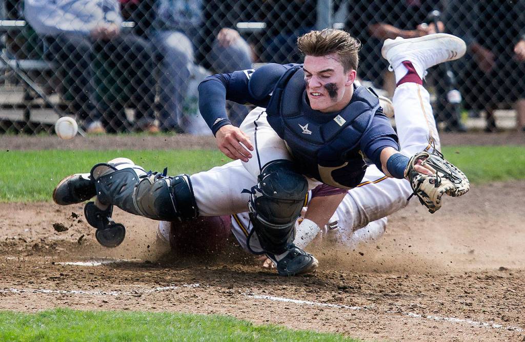 Arlington catcher Jack Sheward is hit in the leg as ODeas David Sessoms slides in for the tying run in the sixth inning. (Andy Bronson / The Herald)