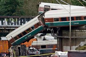FILE - In this Dec. 18, 2017 file photo, cars from an Amtrak train lie spilled onto Interstate 5 below alongside smashed vehicles as some train cars remain on the tracks in DuPont, Wash. Federal investigators are hearing from witnesses Tuesday, July 10, 2018, as they look into last years Amtrak train derailment south of Seattle, Wash., that killed three people and injured dozens. (AP Photo/Elaine Thompson, File)