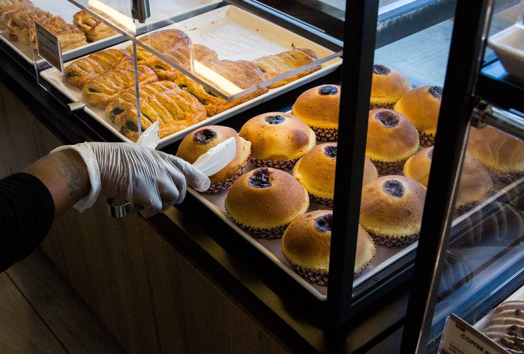 A worker places berry tarts into a self-serve case at Edmonds 85°C Bakery Cafe. (Olivia Vanni / The Herald)