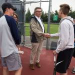 The Arlington doubles team of Ben Spores (left) and Ben Nichols (second from right) meet Doug Grimmius (center), a 1969 Arlington High School graduate and the first Eagles boys tennis player to make state, before practice on May 21 in Arlington. Arlington head coach Ben Mendro is at right. (Andy Bronson / The Herald)
