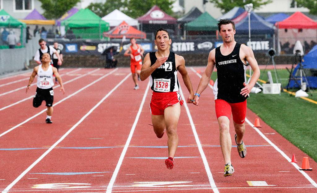 Snohomish sophomore Humoody Smith (1528) and guide Zebedee Kumley cross the finish line to win the boys ambulatory 200-meter race. (Andy Bronson / The Herald)