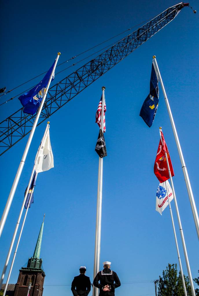 Members of the Everett Naval Base Color Guard stand below raised flags during the Veterans Memorial Commissioning Ceremony at the Snohomish County Plaza on May 23 in Everett. (Olivia Vanni / The Herald)